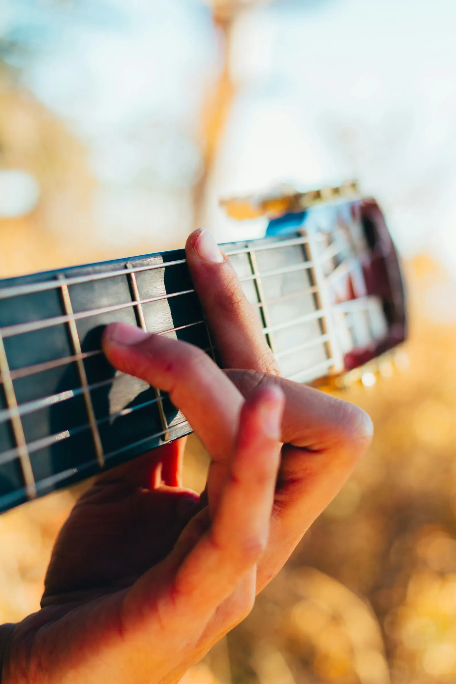 A hand frets the strings of a guitar