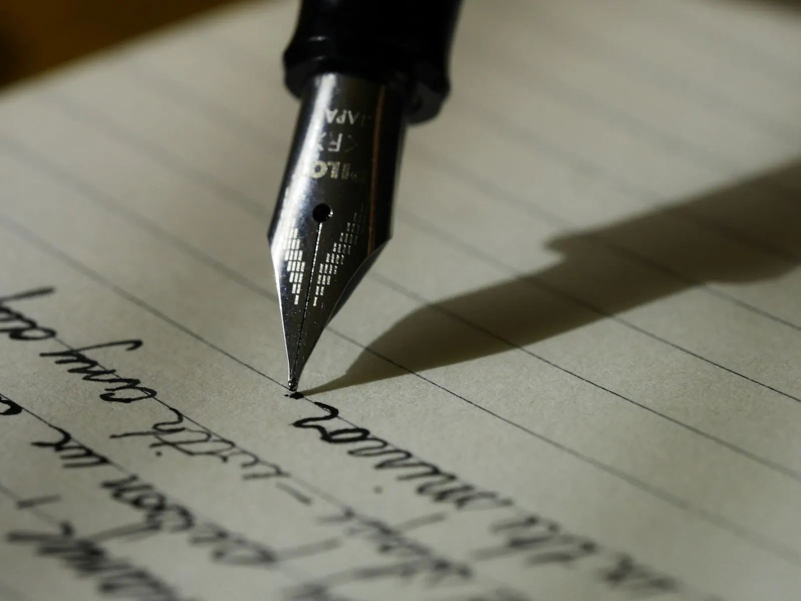 A fountain pen writes on lined paper